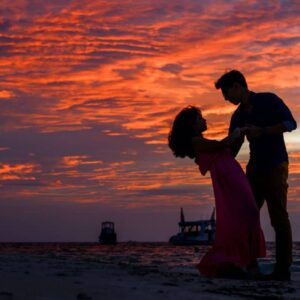 Man and Woman dancing at sunset with boats in the distance