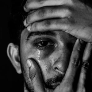 Crying man covering face with his hands